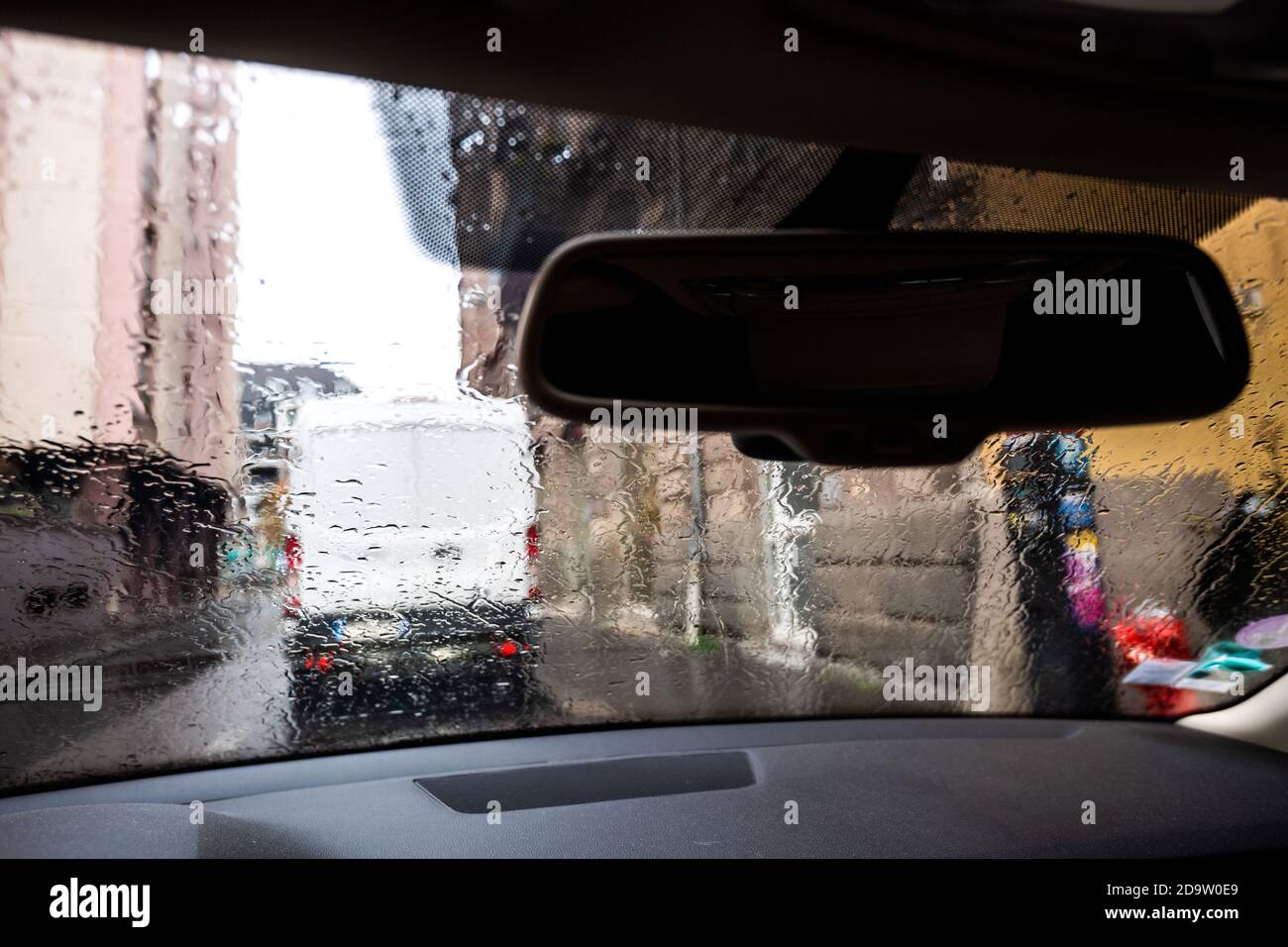 Vista a través del parabrisas del coche con gotas de lluvia el día de otoño En París con la silueta de una furgoneta blanca aparcada en frente Foto de stock