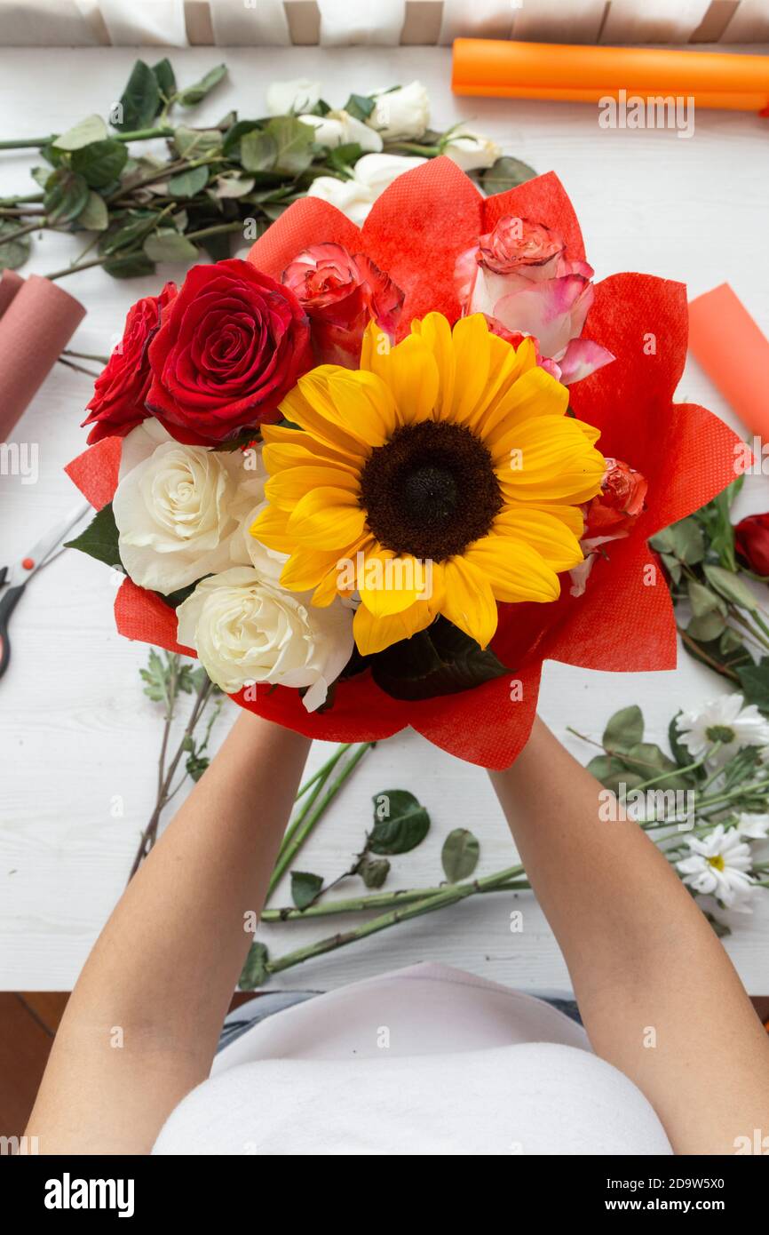 hermoso arreglo floral hecho con rosas rojas y blancas y girasol, en el  fondo cardboards y tijeras Fotografía de stock - Alamy