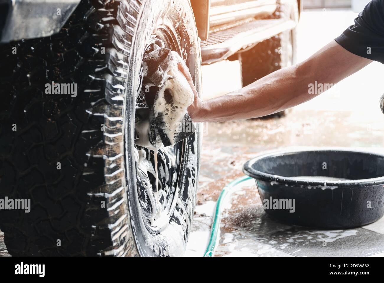 El personal de lavado de automóviles está usando una esponja humedecida con agua y jabón para limpiar las ruedas del auto. Foto de stock