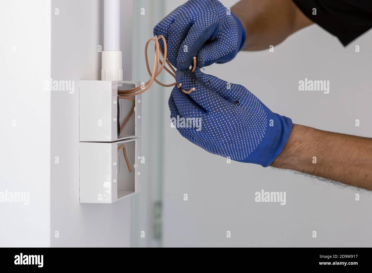 https://c8.alamy.com/compes/2d9w917/el-electricista-usa-guantes-azules-esta-usando-un-cuchillo-electrico-para-cortar-el-cable-para-instalar-el-enchufe-y-el-interruptor-de-alimentacion-en-la-pared-2d9w917.jpg
