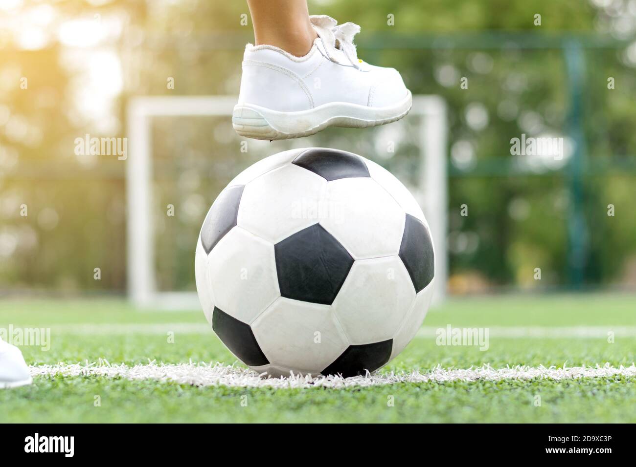 insuficiente Permuta Mount Bank Pies de un niño con zapatillas blancas pisando una pelota de fútbol en el  medio del campo de fútbol Fotografía de stock - Alamy