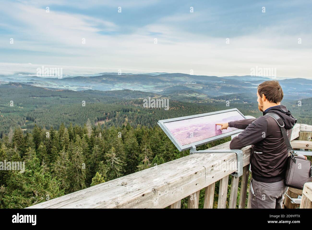 Hombre en la torre de observación buscando en un mapa.mochilero macho disfrutando Vista de paisaje brumoso.Hombre Viajero en la cumbre de montaña de Boubin checo.Viajes Foto de stock