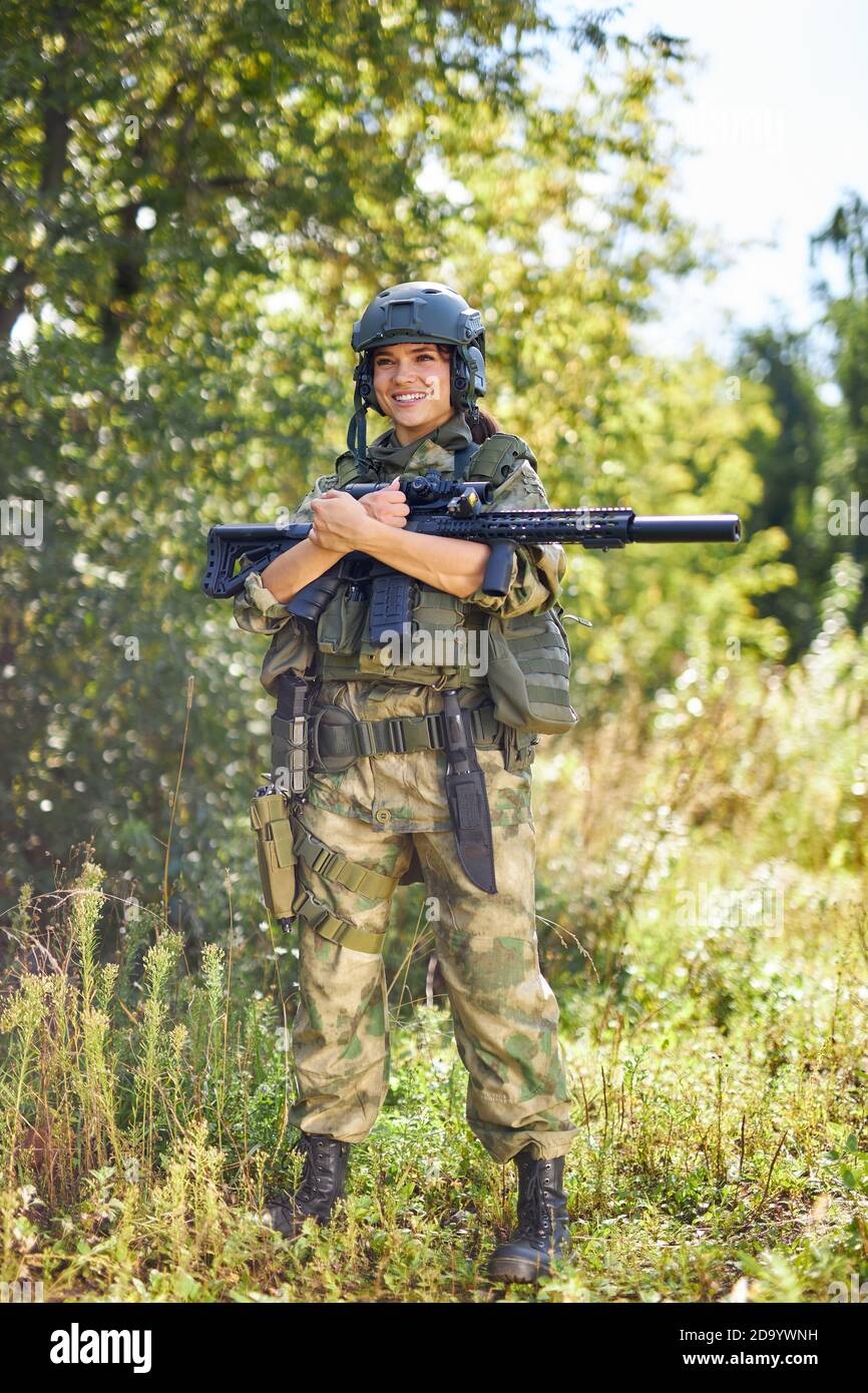 retrato de una mujer militar segura con un arma en el bosque