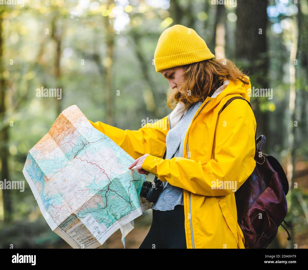 Vista lateral de mujer explorador en chubasquero amarillo y con mochila de  pie en el bosque y la búsqueda de la ruta en el papel mapa Fotografía de  stock - Alamy