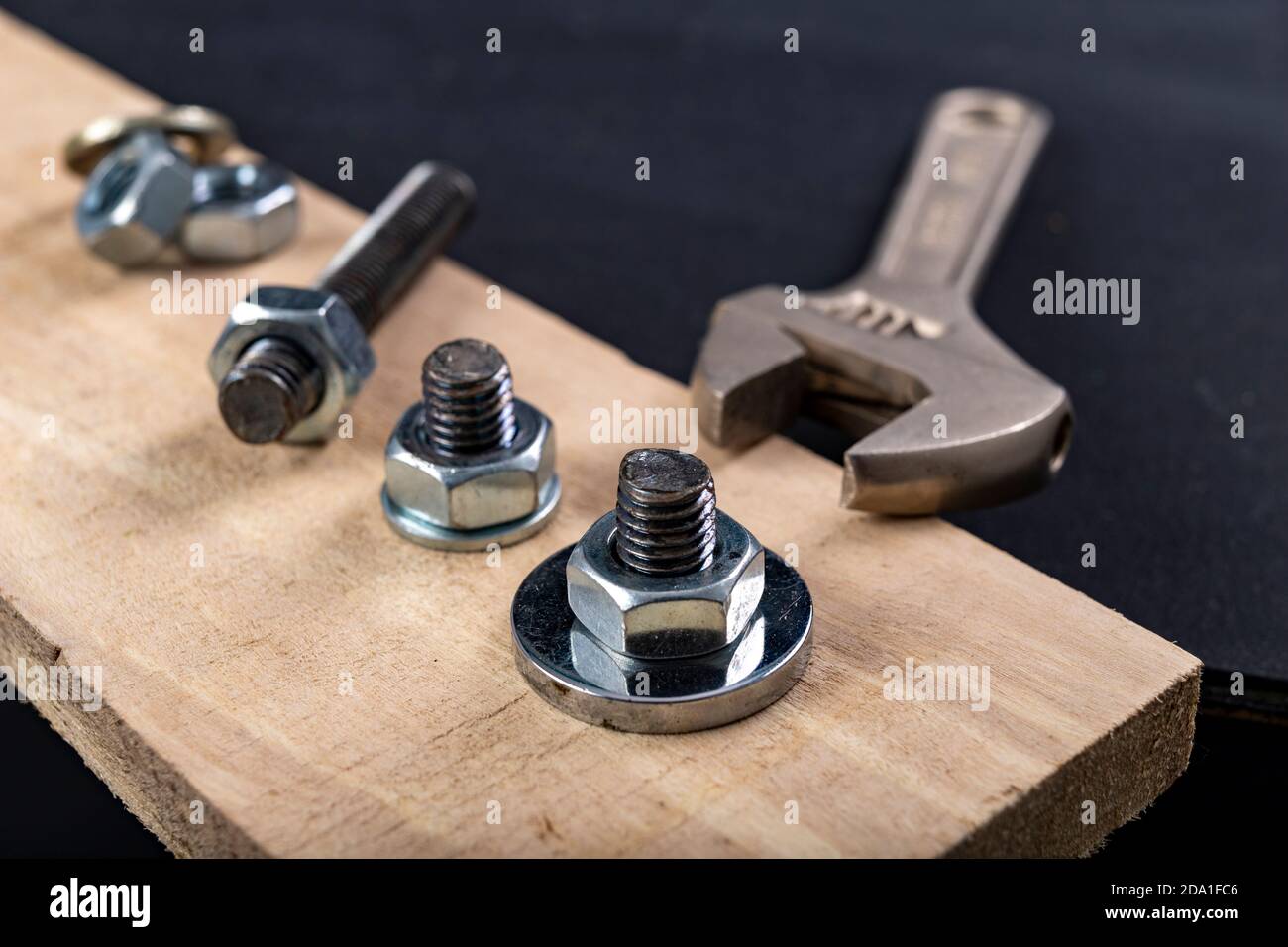 Pernos y tuercas de metal para unir madera. Apriete los tornillos con una  llave ajustable. Fondo oscuro Fotografía de stock - Alamy