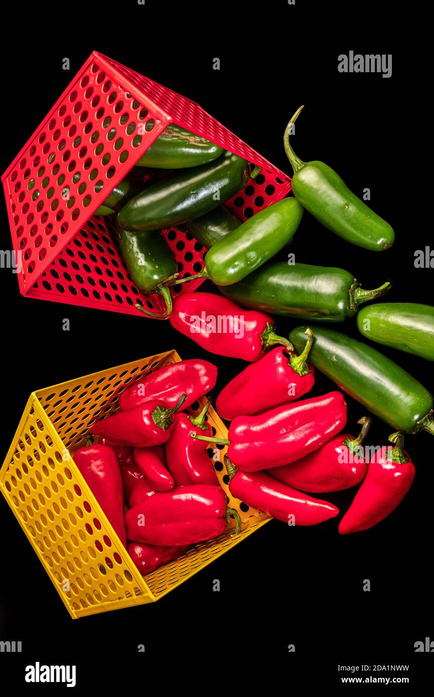 Pimientos rojos y verdes dentro de cestas de metal rojas y amarillas Foto de stock