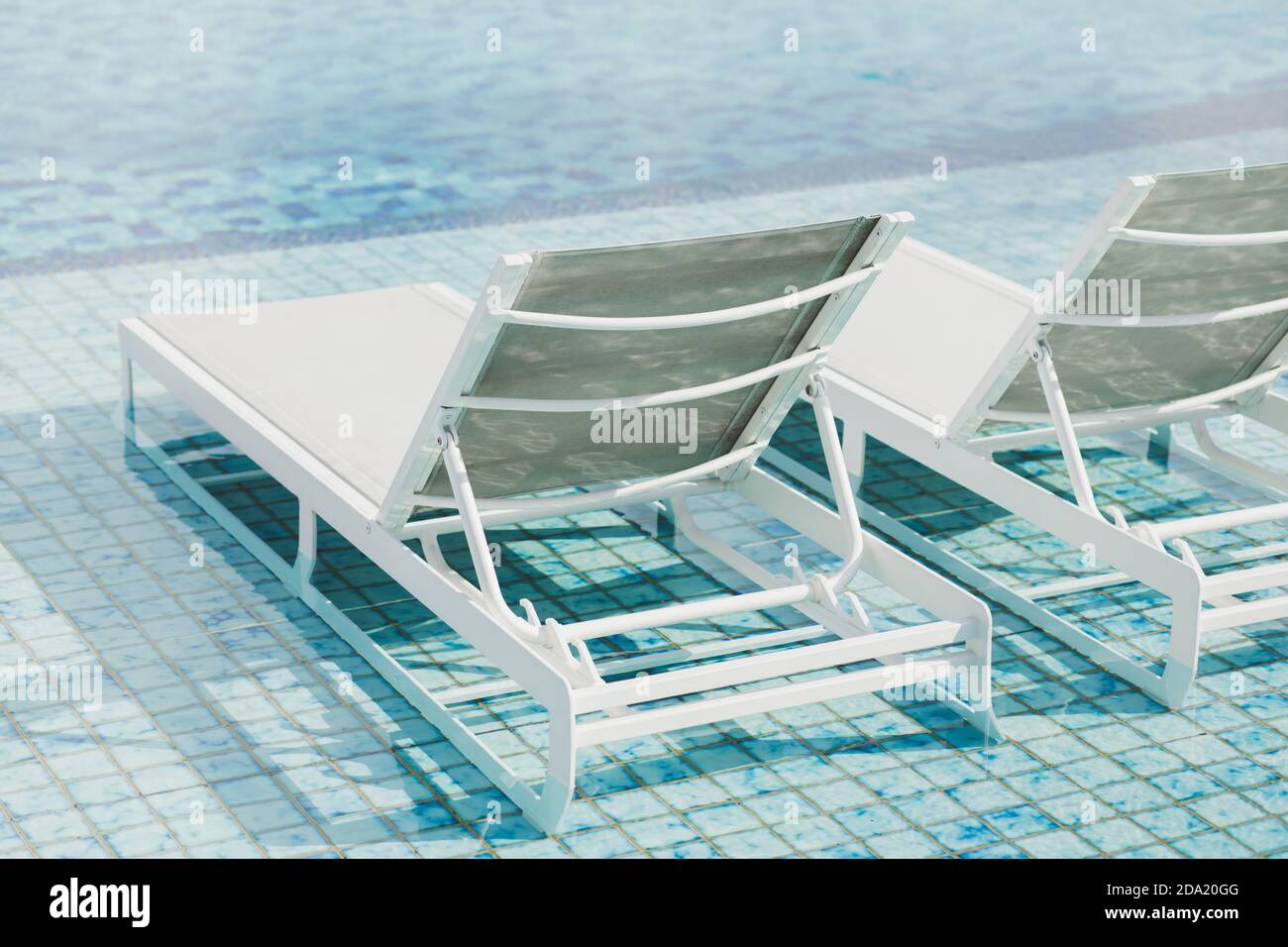 Sillones reclinables de metal blanco al lado de la piscina. Muebles contemporáneos de playa al aire libre. Piscina con agua azul clara. Vacaciones de lujo en Asia. Foto de stock