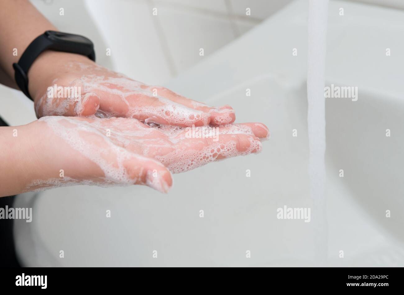 Manos jabonosas sobre el lavabo en el cuarto de baño.Higiene y limpieza de manos. Foto de stock