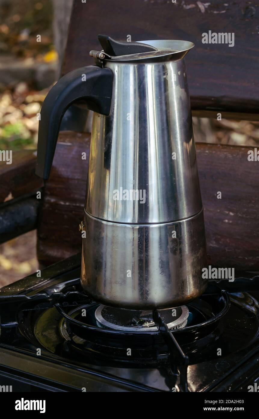 Geyser metal cafetera y estufa de gas portátil en banco del parque. Proceso  de hacer café natural durante el picnic o el viaje. Estilo de vida  Fotografía de stock - Alamy