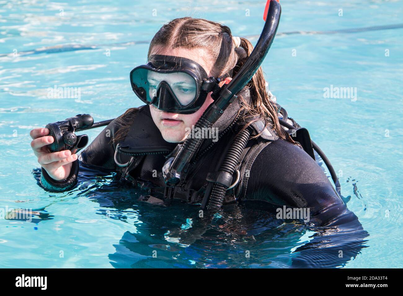 Entrenamiento de buceo en una piscina, una estudiante con un traje de  neopreno y máscara de buceo y regulador en su mano de cerca Fotografía de  stock - Alamy