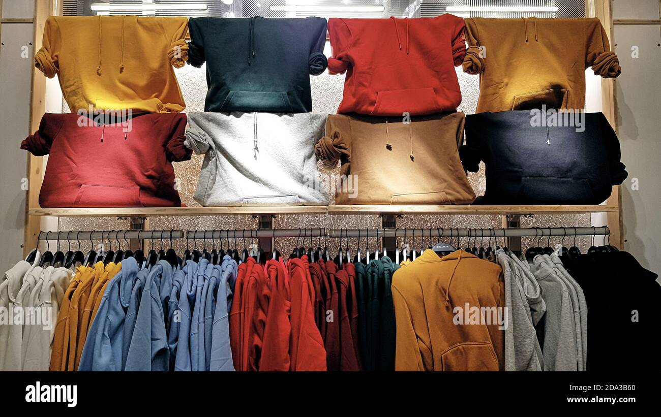 Sudaderas y brillantes colgadas en una tienda de moda. Primer plano de sudaderas multicolor amarillas, rojas, rosadas y géen cuelgan en fila en un suspensor Fotografía de stock - Alamy