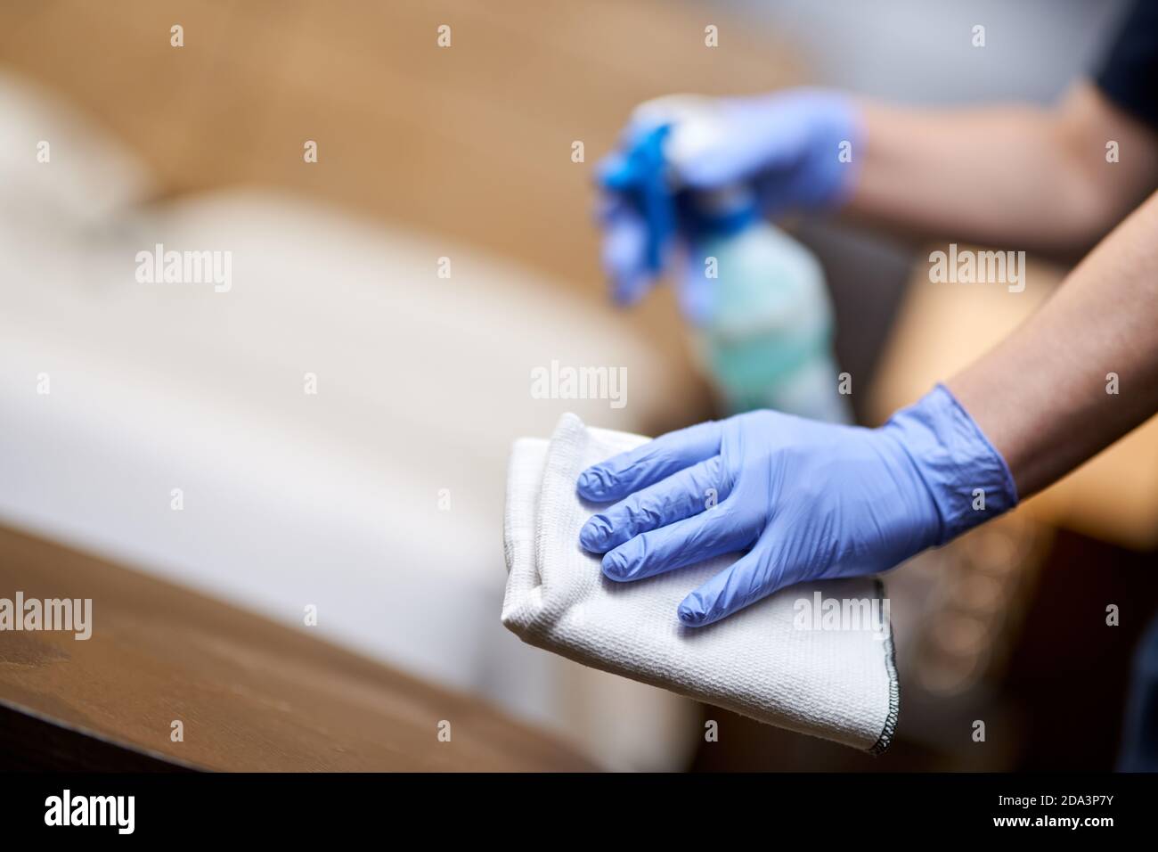Mujer mano en un guante sosteniendo un trapo de limpieza blanco en una habitación de hotel. Espacio de copia. Concepto de limpieza e higiene Foto de stock