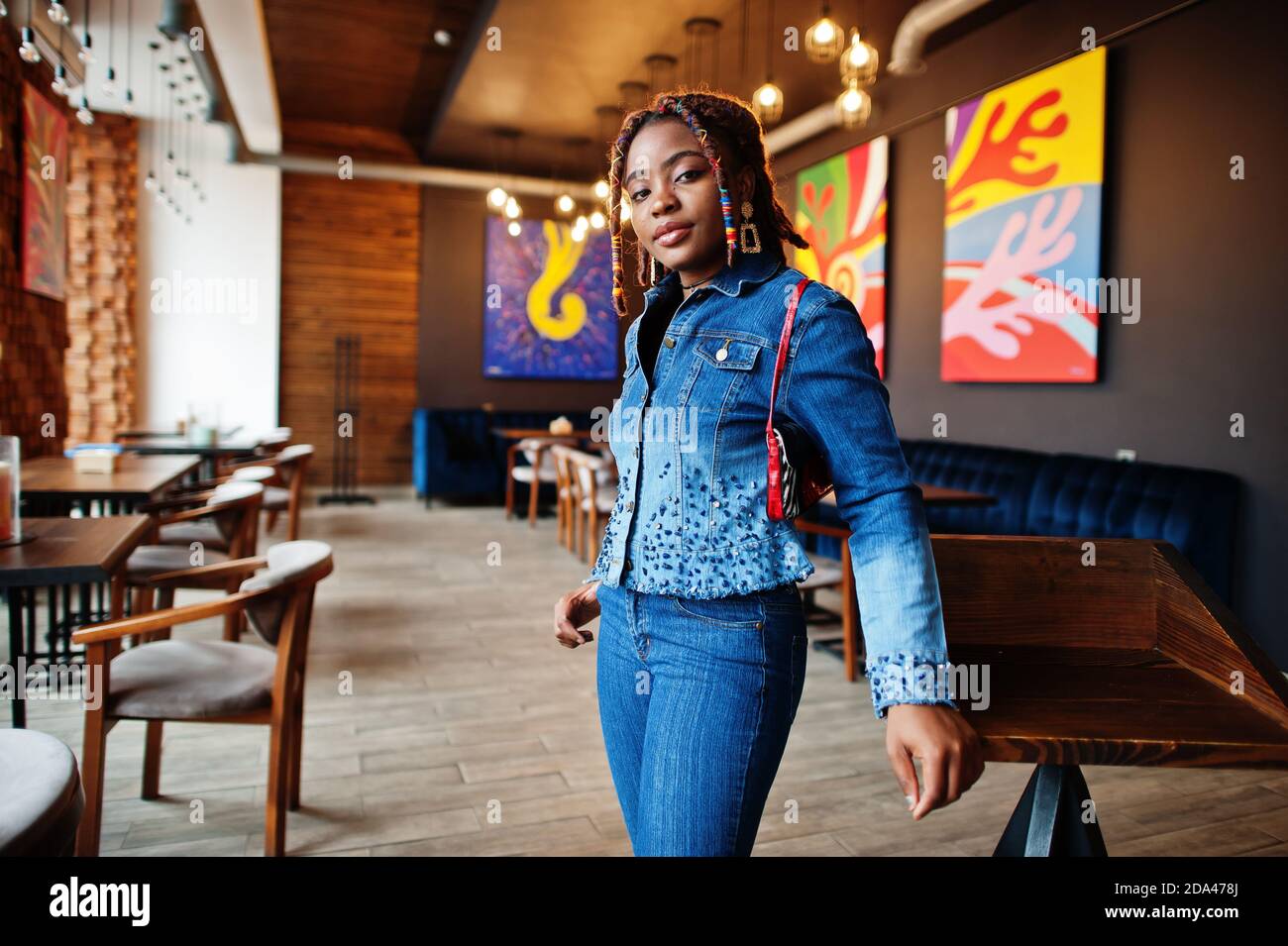 Encantadora mujer afroamericana con dreadlocks en azul elegante chaqueta  vaquera en el café. Hermoso fresco de moda negro joven interior Fotografía  de stock - Alamy