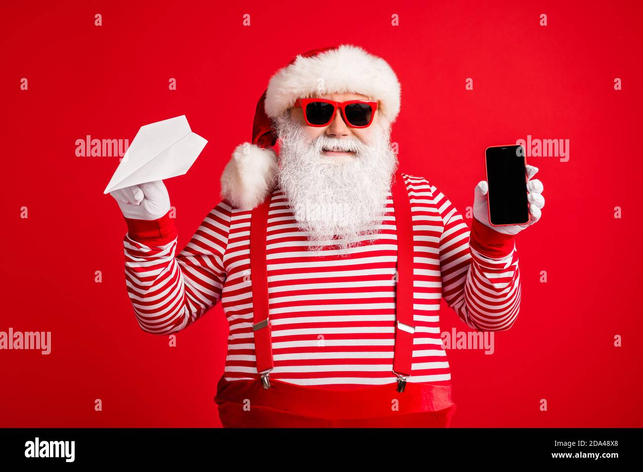 Foto de hombre viejo barba gris sostener origami avión teléfono pantalla  espacio vacío vestir santa claus x-mas disfraz suspenders gafas de sol  gorra de rayas Fotografía de stock - Alamy