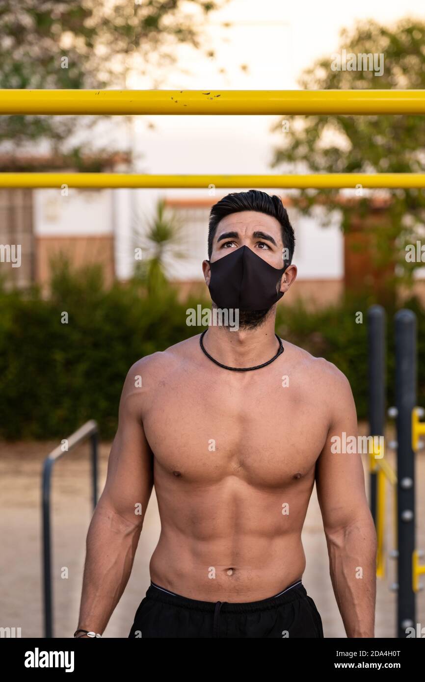 Joven latino con pantalones negros y máscara haciendo ejercicios en un  parque calistenico sin camiseta Fotografía de stock - Alamy