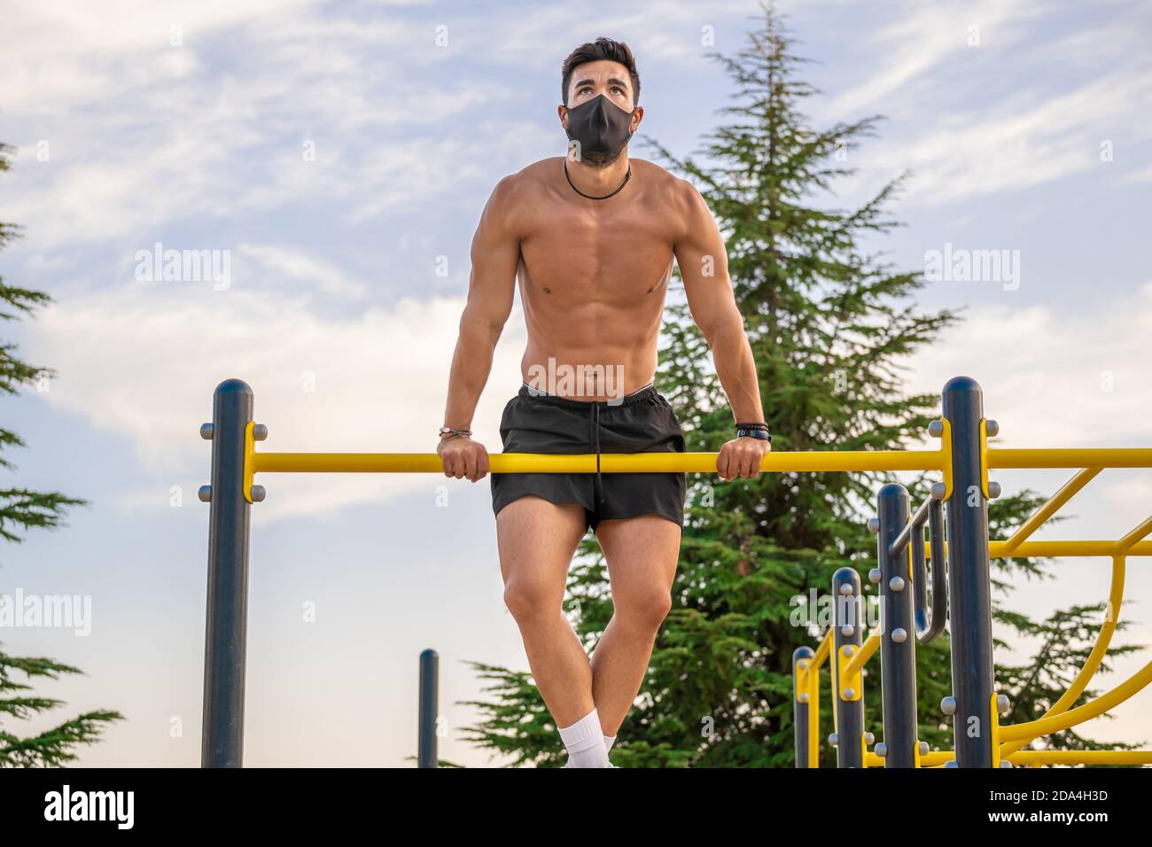 Joven latino sin camisa y pantalones negros y. máscara haciendo pull-ups en  un bar del parque calistenics Fotografía de stock - Alamy