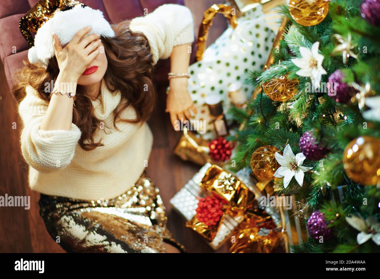 Feliz Navidad. Vista superior de la mujer moderna estresada en falda de  lentejuelas de oro y suéter cerca del árbol de Navidad y cajas de regalo  Fotografía de stock - Alamy