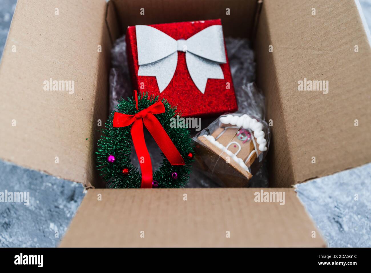 Paquete postal con artículos de Navidad dentro de ella incluyendo brillante  presente, corona y casa de pan de jengibre, concepto de comprar o enviar  regalos onl Fotografía de stock - Alamy