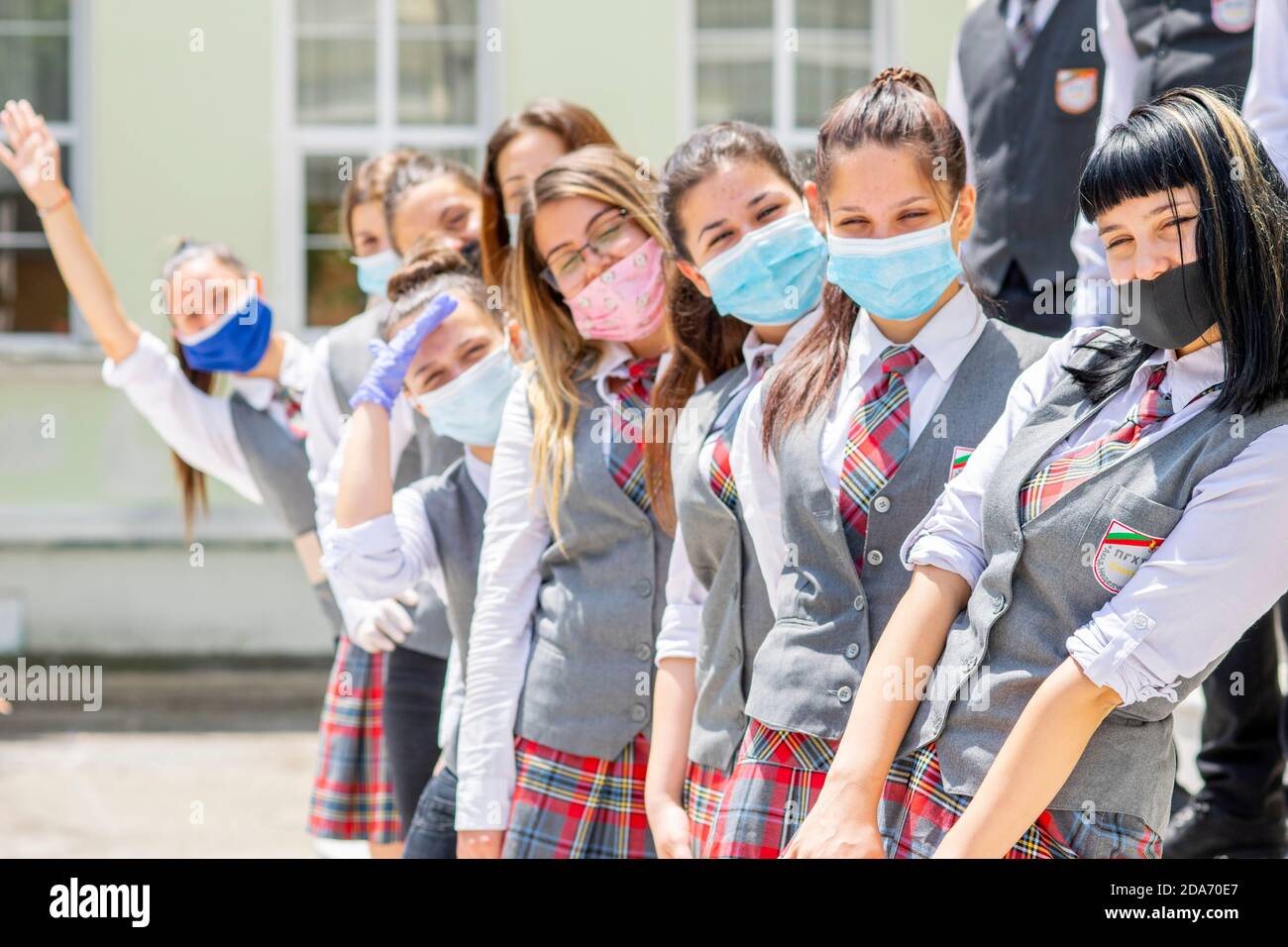 Sliven, Bulgaria - 11 de junio de 2020: Niñas que se preparan para la graduación de la escuela secundaria durante el distanciamiento social del coronavirus Covid-19, llevando la cara cubierta / m Foto de stock