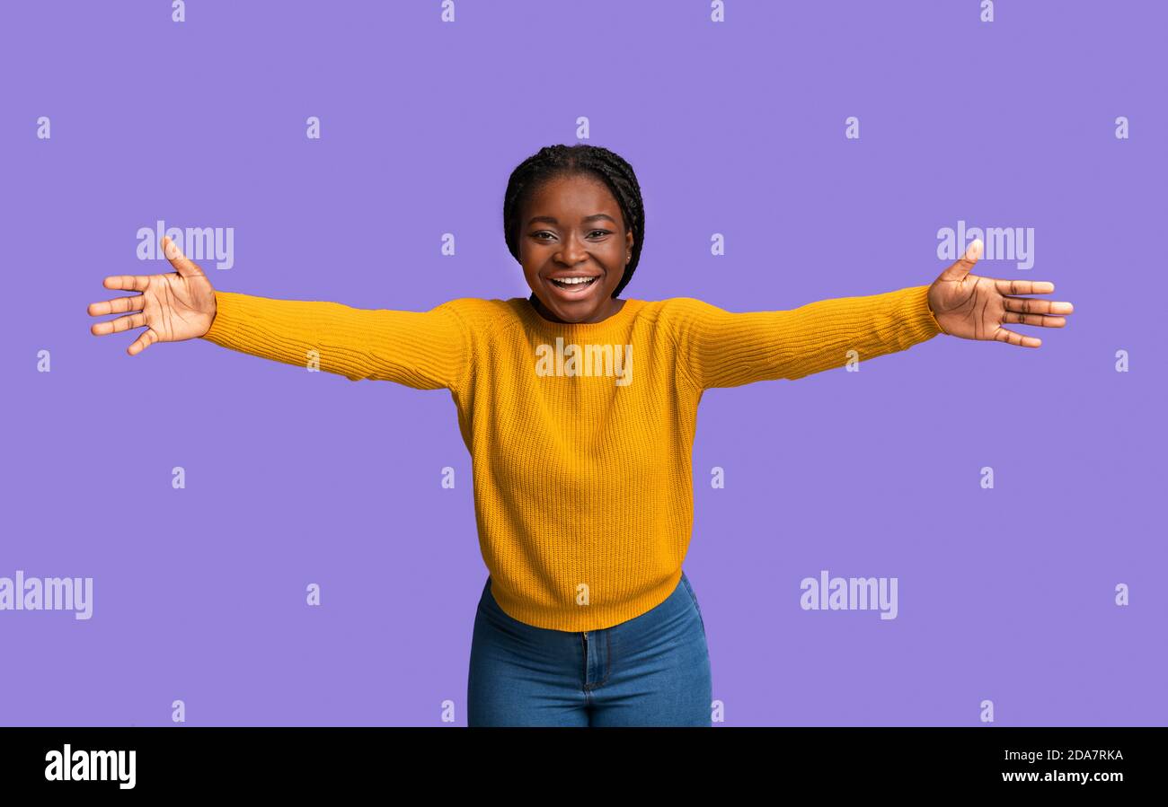 Una mujer afroamericana amistosa que tira de las manos hacia la cámara, saludando a alguien Foto de stock