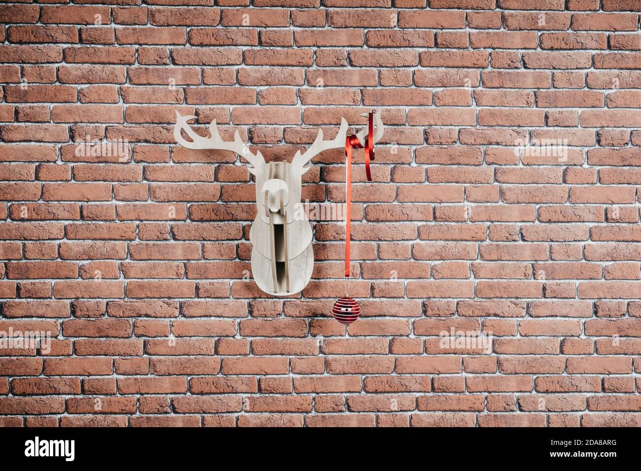 Ciervo de madera colgado en la pared decorado con guirnaldas y bola de Navidad. Foto de stock