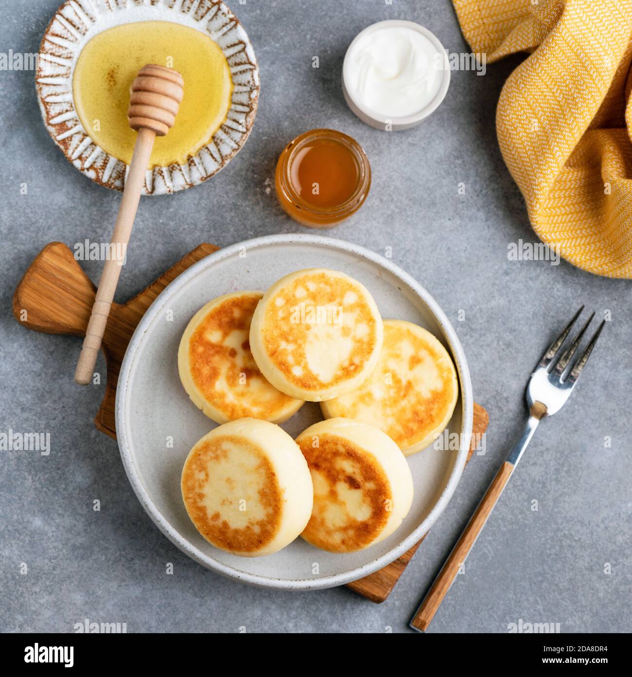 Fritters de queso cottage servidos con miel sobre fondo de hormigón, vista superior Foto de stock