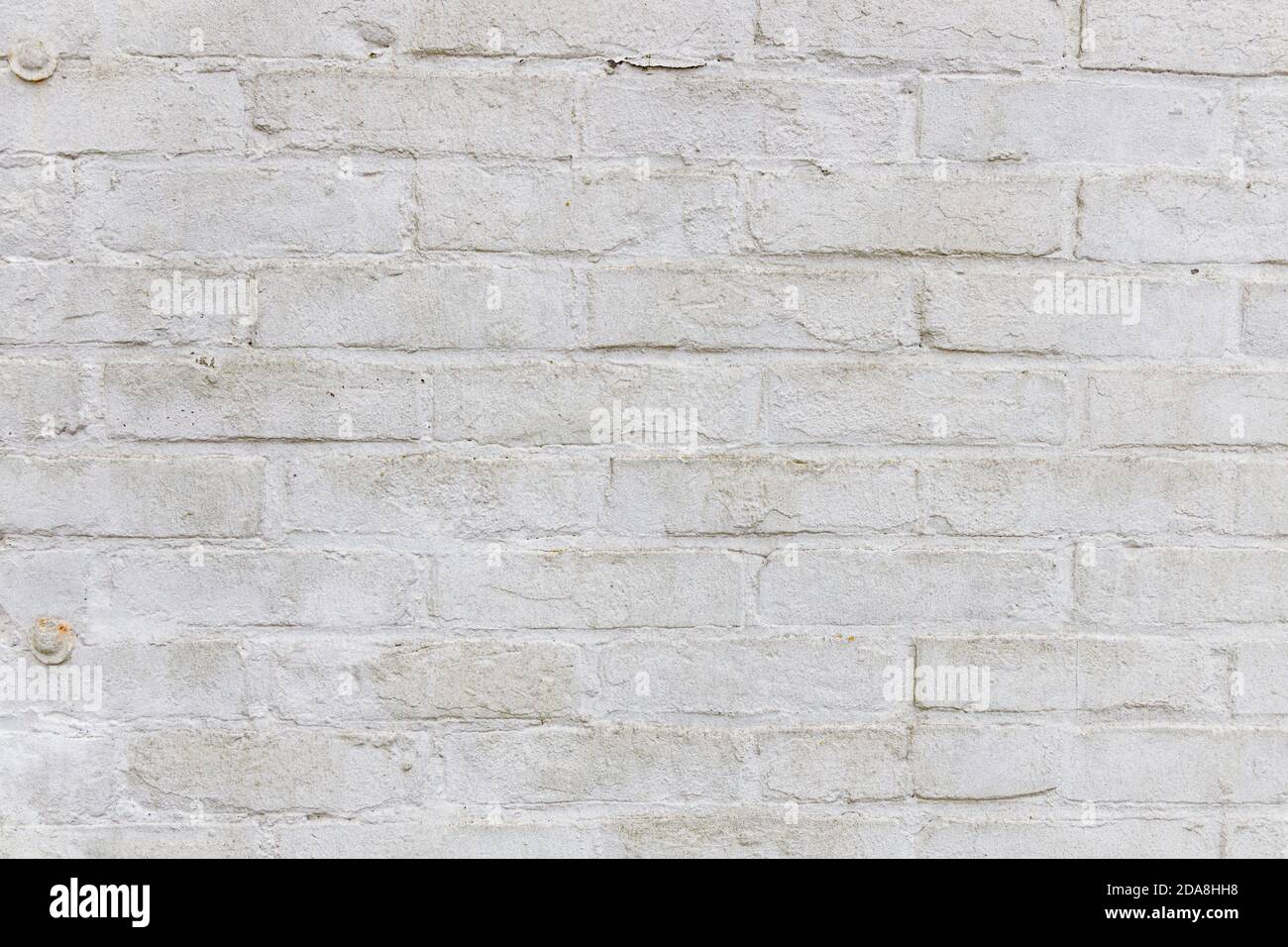 Textura de una pared de ladrillo erosionada blanca con pintura blanca gruesa, pequeñas abolladuras y arañazos con algún grado de gruñido y suciedad, uso para el modelo de juego Foto de stock