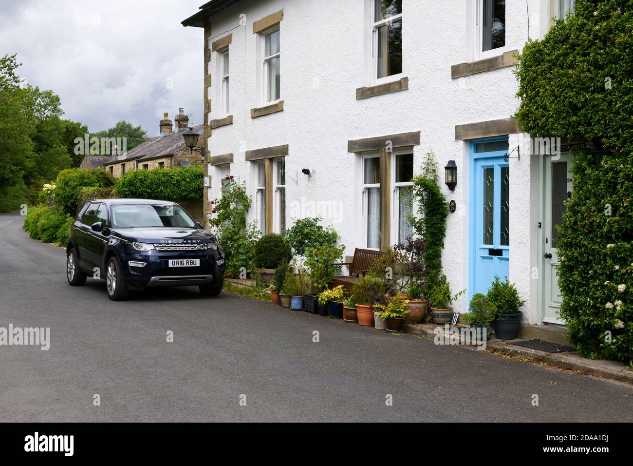 Fila de tradicionales casas de piedra blanca en el pintoresco pueblo rural, Land Rover Discovery Sport estacionado en la carretera - Linton, North Yorkshire Inglaterra Reino Unido. Foto de stock