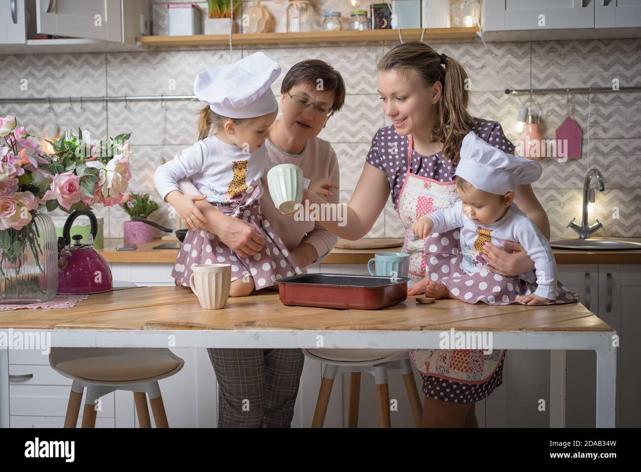 La mamá de la familia, la abuela y dos hermanas cocinan en la cocina. Foto de stock