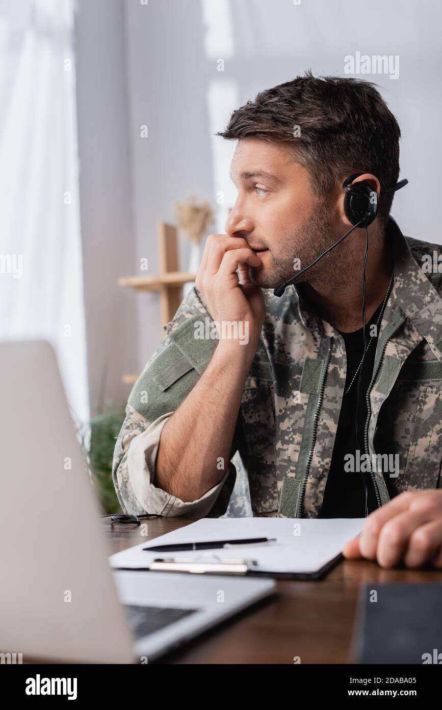 un hombre militar preocupado con uniforme y auriculares mirando hacia fuera  portátil Fotografía de stock - Alamy