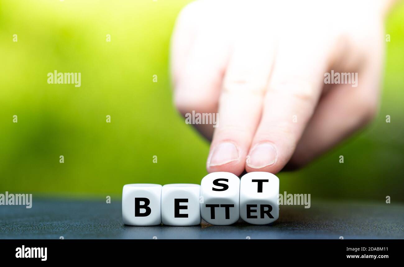 La mano se convierte en dados y cambia la palabra "mejor" a "mejor". Foto de stock