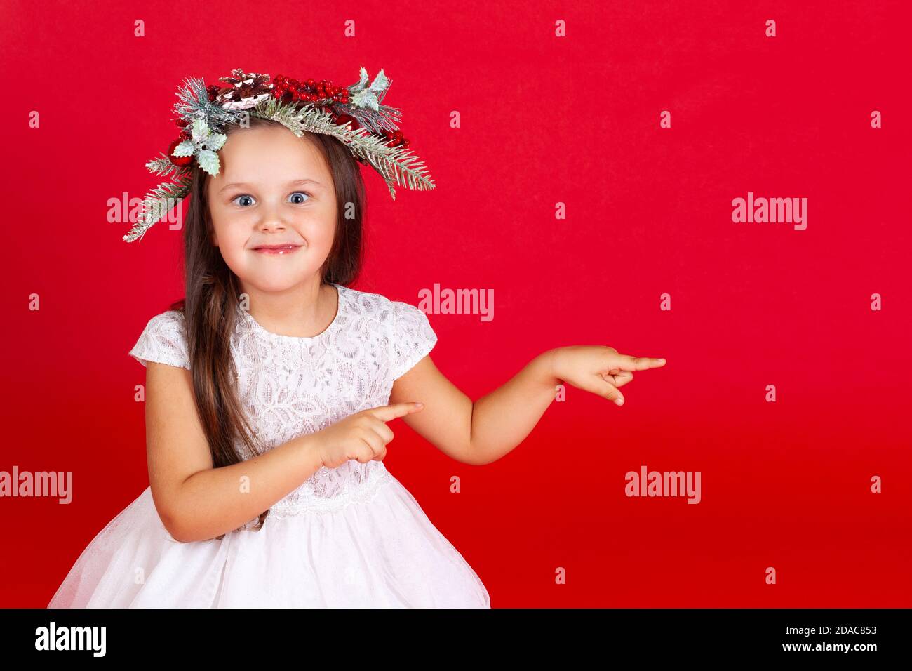 retrato simulado de una chica sorprendida en un vestido de vacaciones, apuntando con sus dedos índice, sobre un fondo rojo Foto de stock