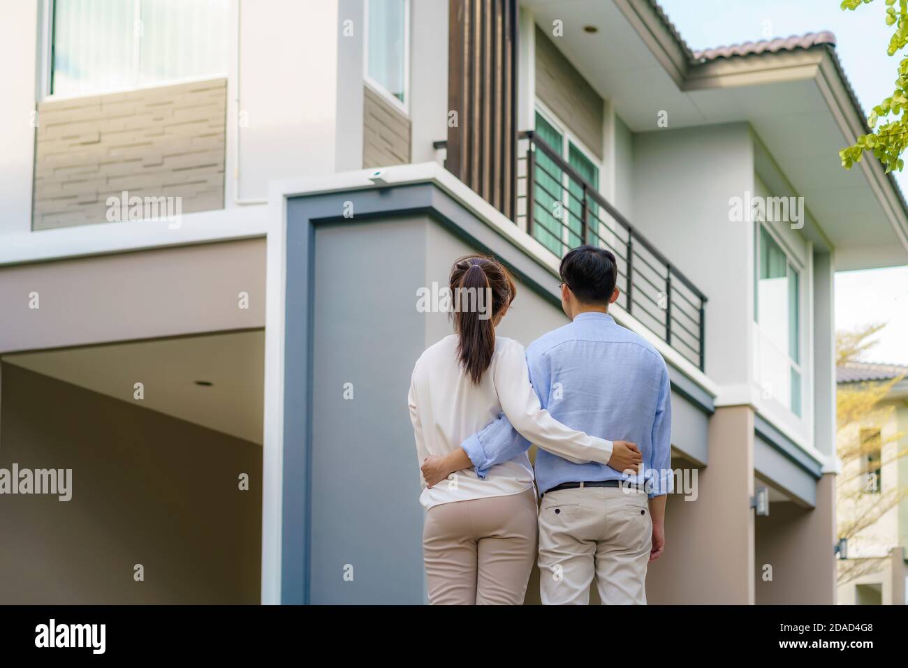 Retrato de una pareja joven asiática de pie y que se acoplan juntos buscando feliz frente a su nueva casa para comenzar una nueva vida. Familia, edad, hogar, verdadera esta Foto de stock