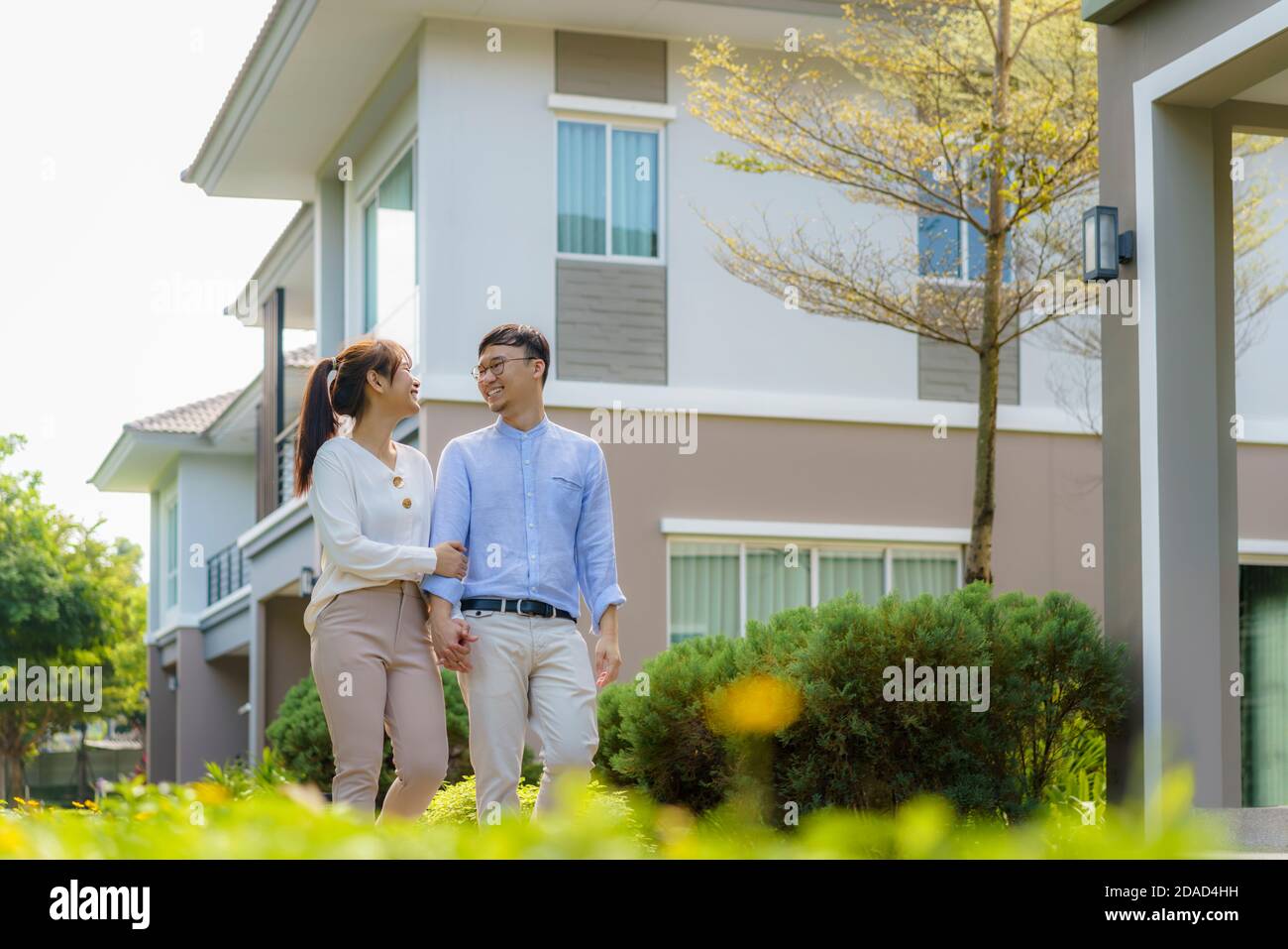Retrato de una pareja asiática caminando y abrazando juntos buscando feliz frente a su nueva casa para comenzar una nueva vida. Familia, edad, hogar, bienes raíces y. Foto de stock