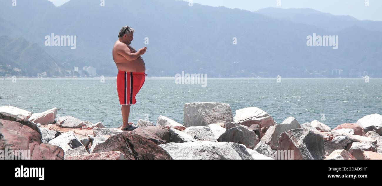 Hombre revisando su teléfono en unas vacaciones de rompeolas en un resort junto al mar Foto de stock