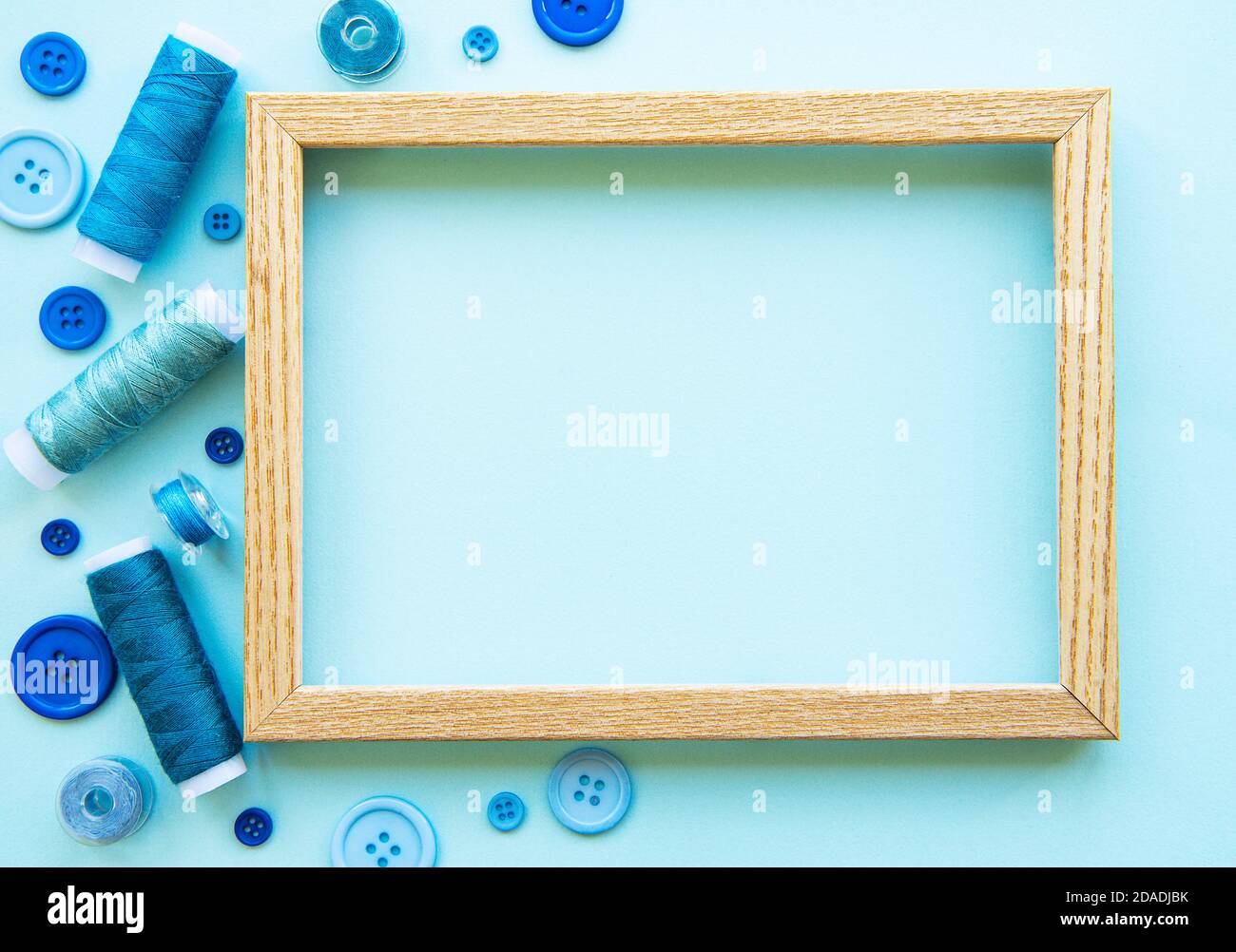 Bobinas de hilo y botones en tonos azules en un fondo azul Foto de stock