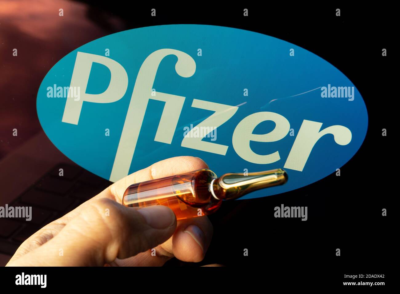 Empresa farmacéutica de vacunas contra el coronavirus de Pfizer. Logotipo de Pfizer con vacuna de sujeción a mano. Foto de stock