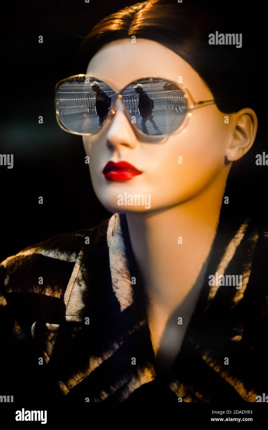 NUEVA YORK, EE.UU. - 16 de septiembre de 2017: Maniquíes con gafas de sol  de moda en una ventana de la tienda en Manhattan. La figura de un hombre se  refleja en