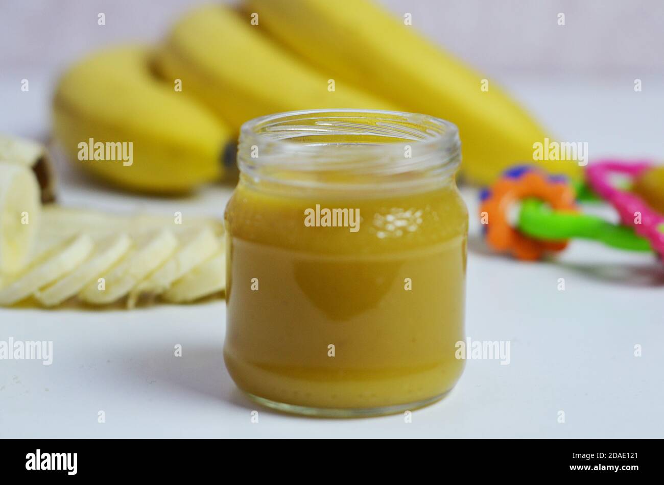 Comida para bebés, puré de patatas y plátanos en un fondo blanco está aislado. Foto de stock