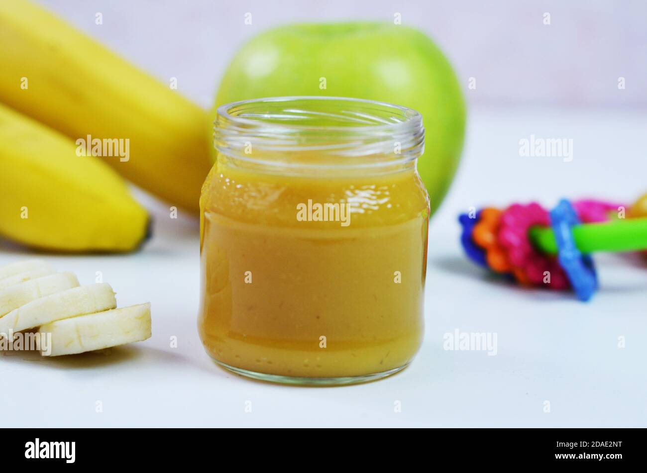 Comida para bebés, puré de patatas y plátanos en un fondo blanco está aislado. Foto de stock