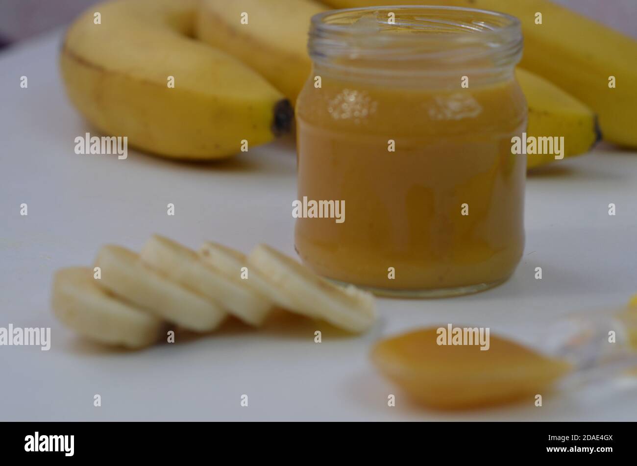 Comida para bebés, puré de patatas y plátanos en un fondo blanco está aislado. Foto de stock