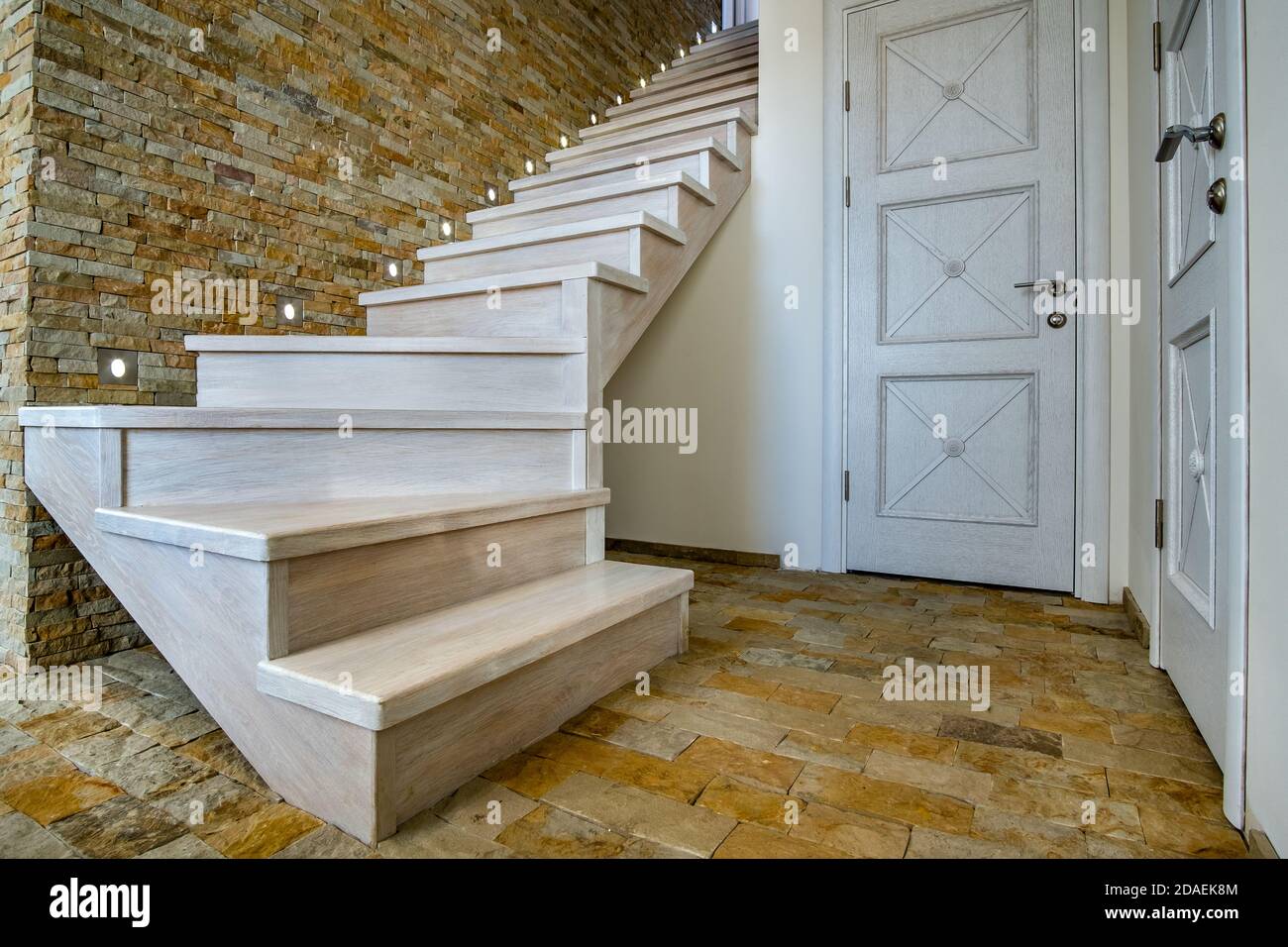 Elegante escalera contemporánea de madera en el interior de la casa loft. Pasillo moderno con paredes decorativas de ladrillo de piedra caliza y escaleras de roble blanco. Foto de stock