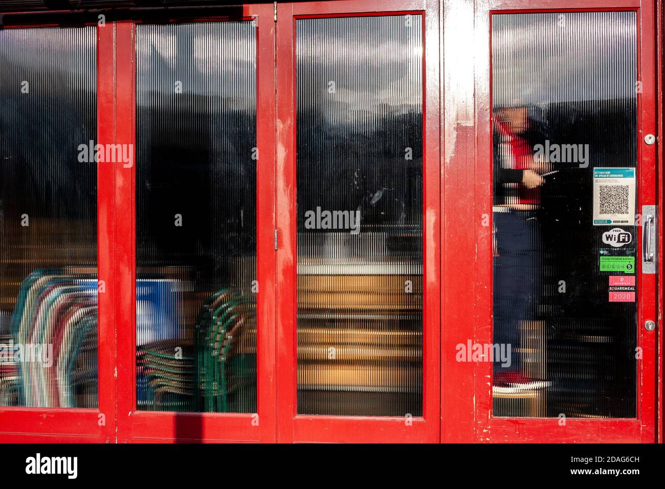 Un hombre lleva a cabo reparaciones de bricolaje detrás de vidrio esmerilado en el interior de un bar/restaurante durante el cierre 2. Londres Foto de stock