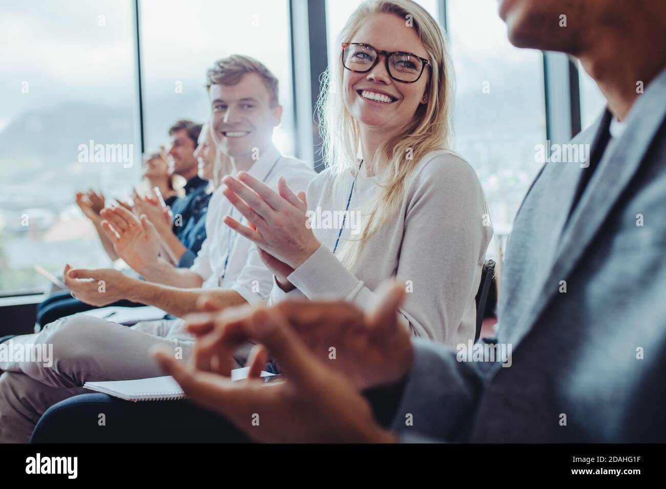 Grupo de empresarios sentados en el seminario golpeando las manos. Hombres de negocios y mujeres de negocios aplaudiendo después de una presentación exitosa en una conferencia. Foto de stock