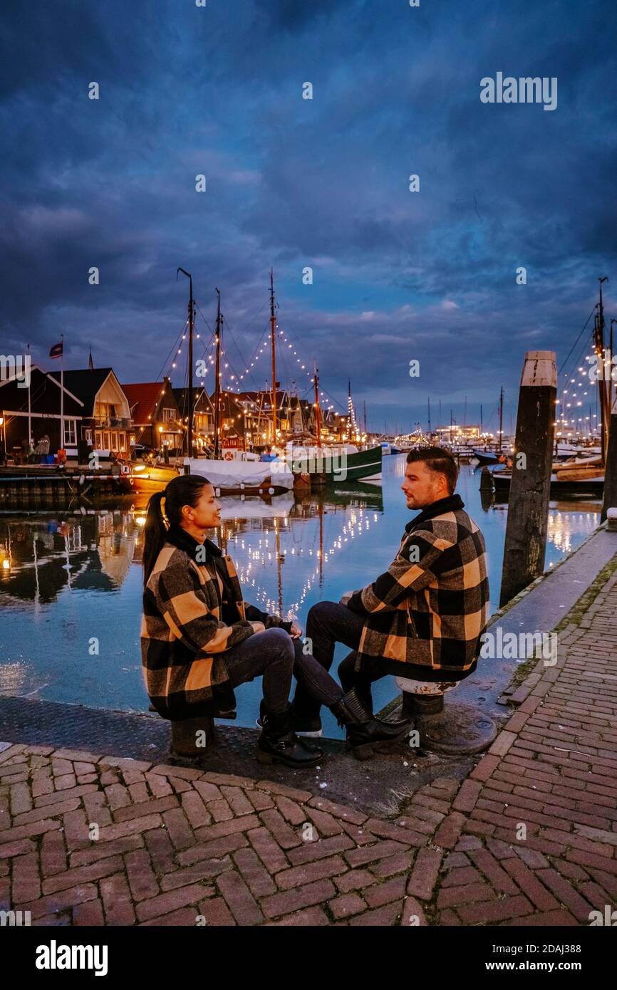 Urk Flevoland Holland, pareja hombres y mujer viendo la puesta de sol en el Pequeño pueblo pesquero puerto de Urk países Bajos Foto de stock