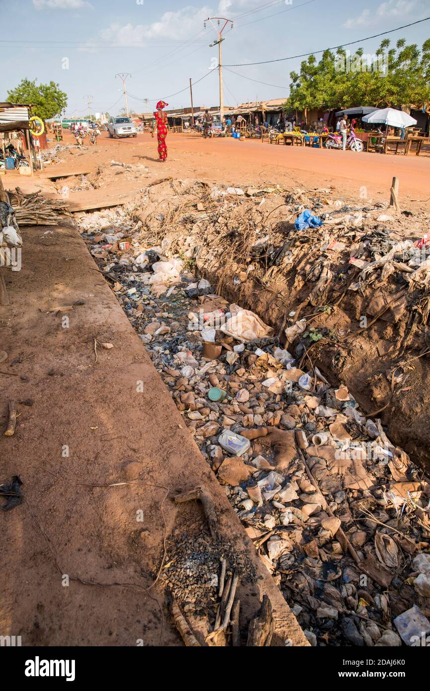 Selingue, Malí, 25 de abril de 2015; bolsas de plástico y basura llenan los desagües pluviales de la calle principal. Foto de stock