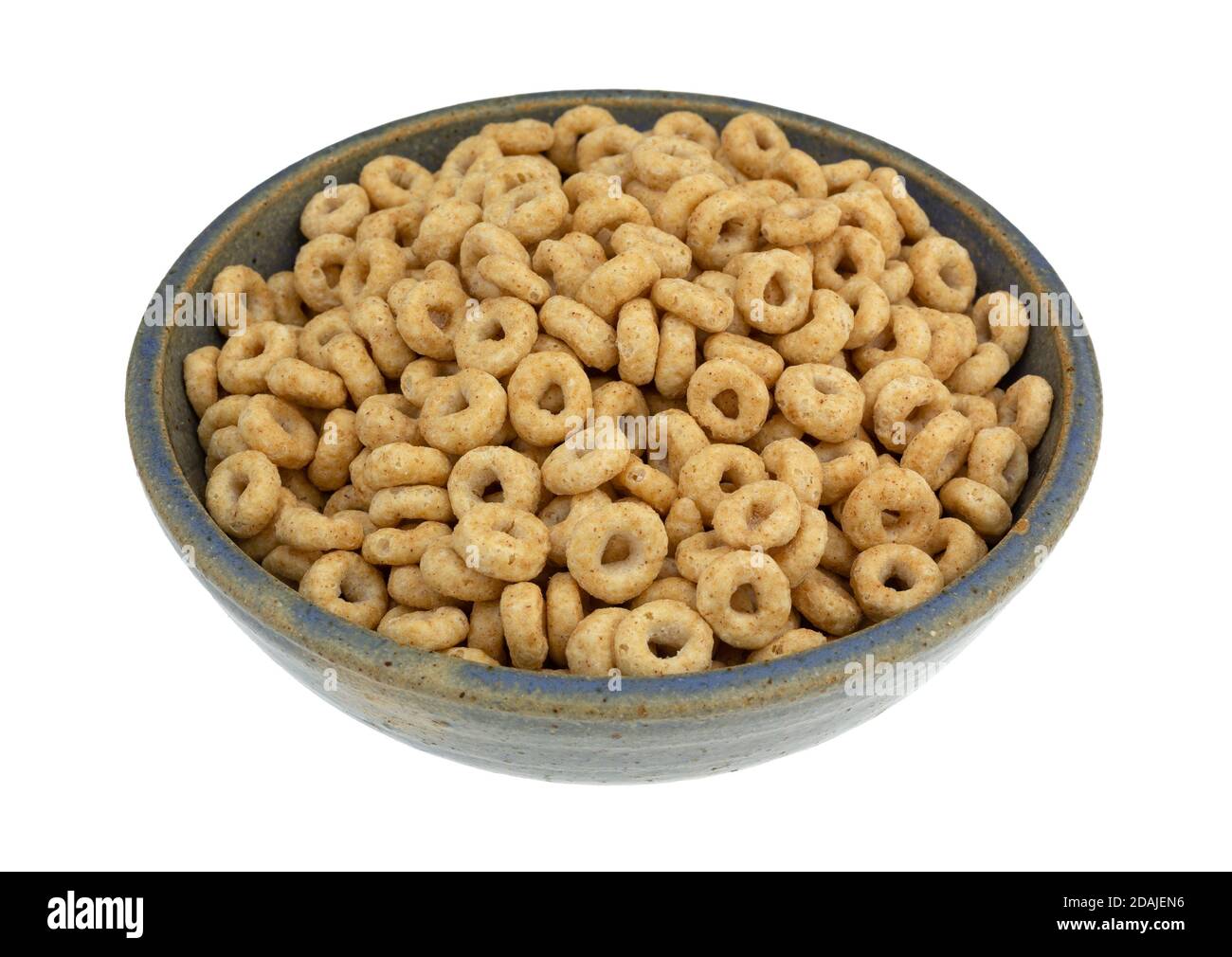 Cereal de avena de grano entero redondo genérico seco en un viejo cuenco de gres azul aislado sobre un fondo blanco. Foto de stock