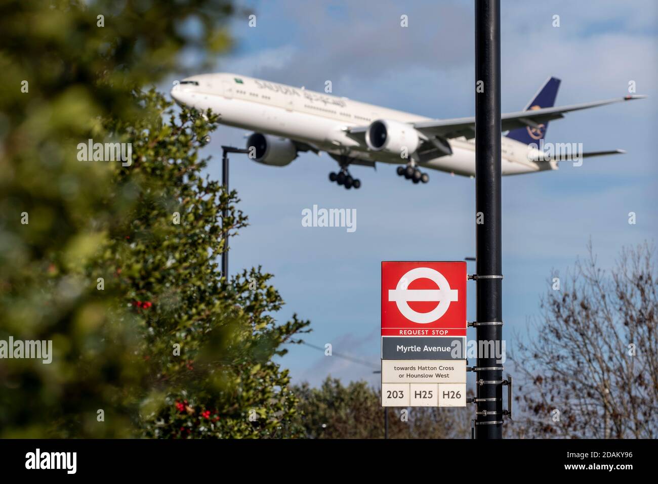 Avión jet airliner en aproximación a la tierra en el Aeropuerto Heathrow de Londres, Reino Unido, sobre la señal de parada de autobús de la avenida Myrtle. Transporte de Londres. Transporte a Londres Foto de stock