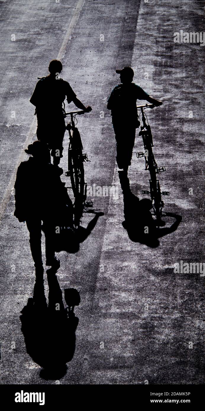 Sombras peatonales en una carretera de techo negro. Una sombra es un área oscura (imagen real) donde la luz de una fuente de luz es bloqueada por un objeto opaco. Foto de stock