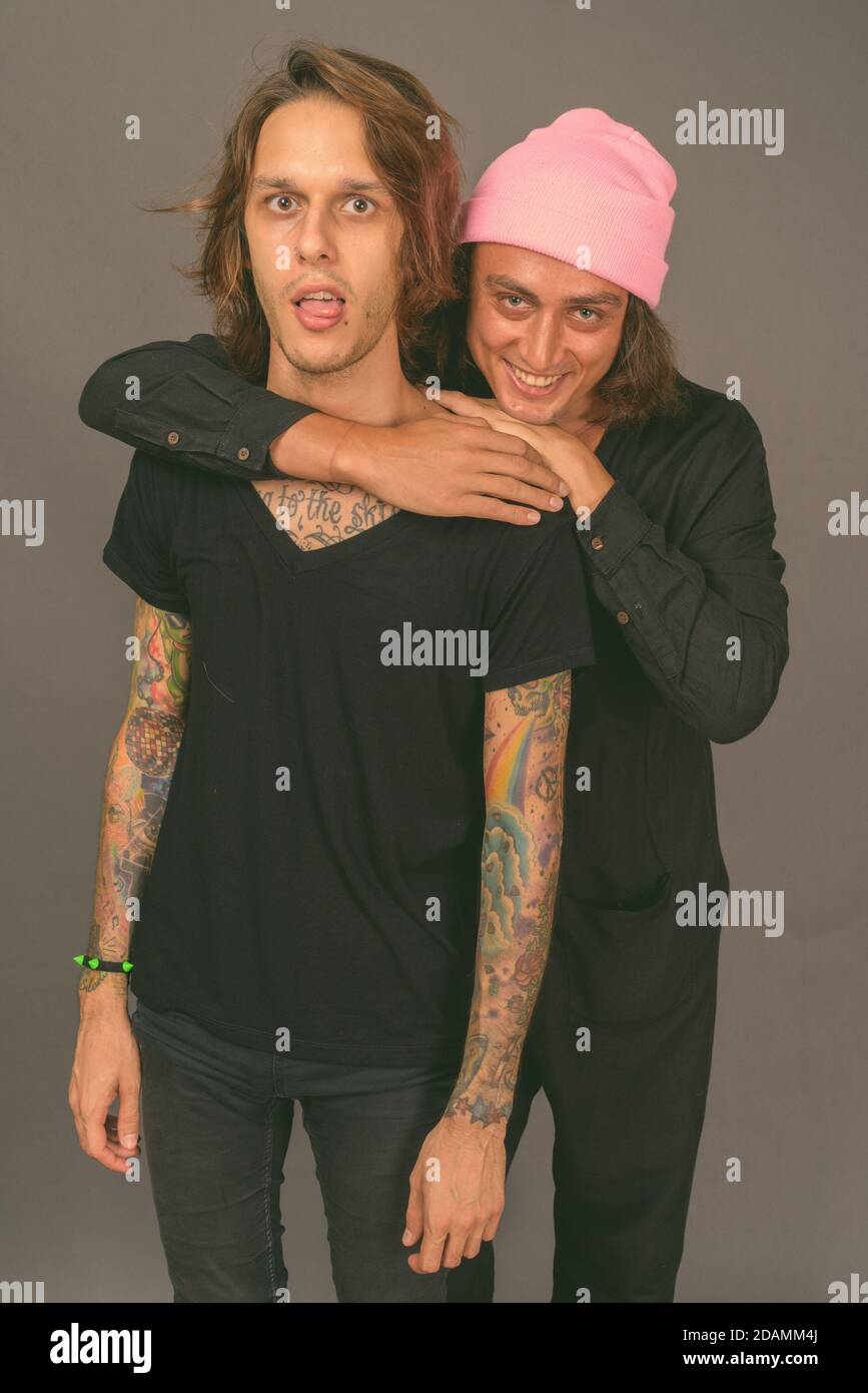 Dos jóvenes hombres guapos juntos contra el fondo gris Fotografía de stock  - Alamy